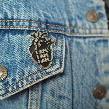 Close up on denim jacket of the Black Anatomical Heart enamel pin featuring a quote by Sylvia Plath Bell Jar - Feminist Poet Writer