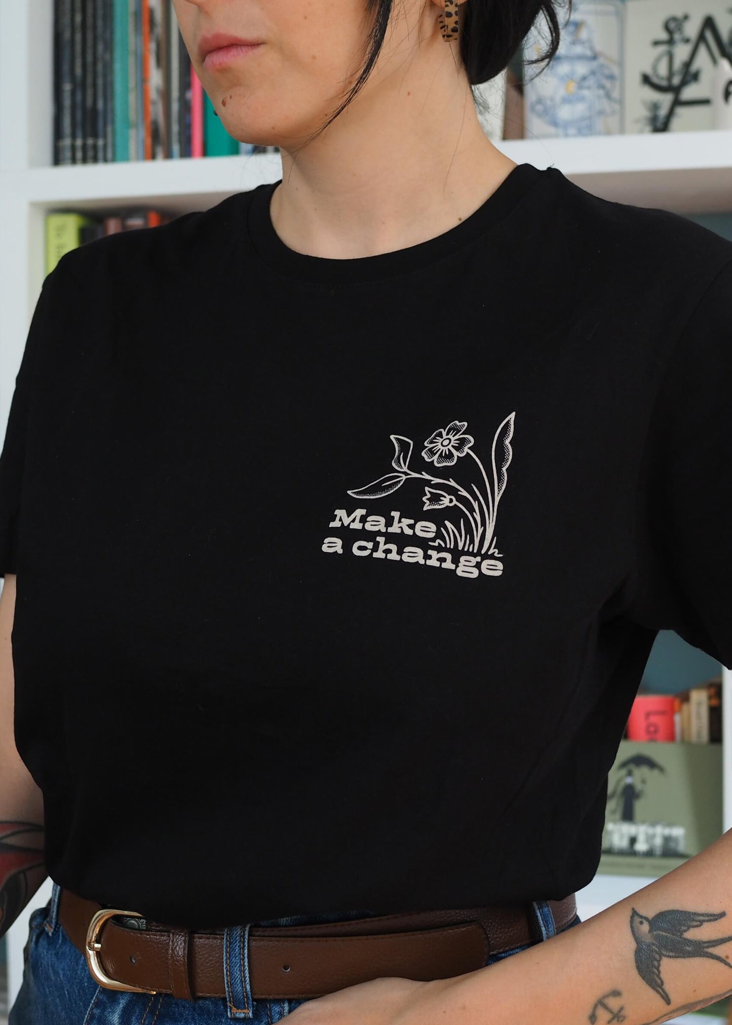 Close up of the screen printed 'Make a Change' eco-conscious graphic detail featuring a stylized flower on black cotton t-shirt